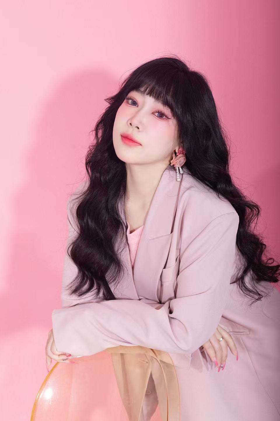 杨頔粉色背景艺术照，坐姿半身形象
